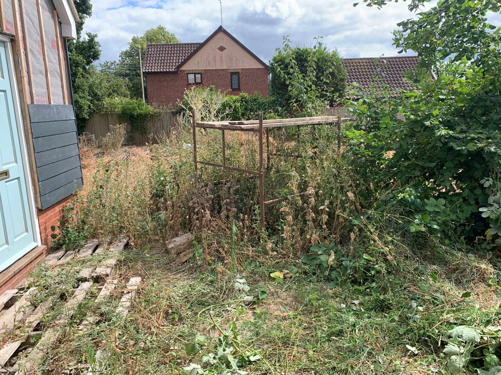 Overgrown plot in Kelsale with old metal frame, before and after clearing (before)