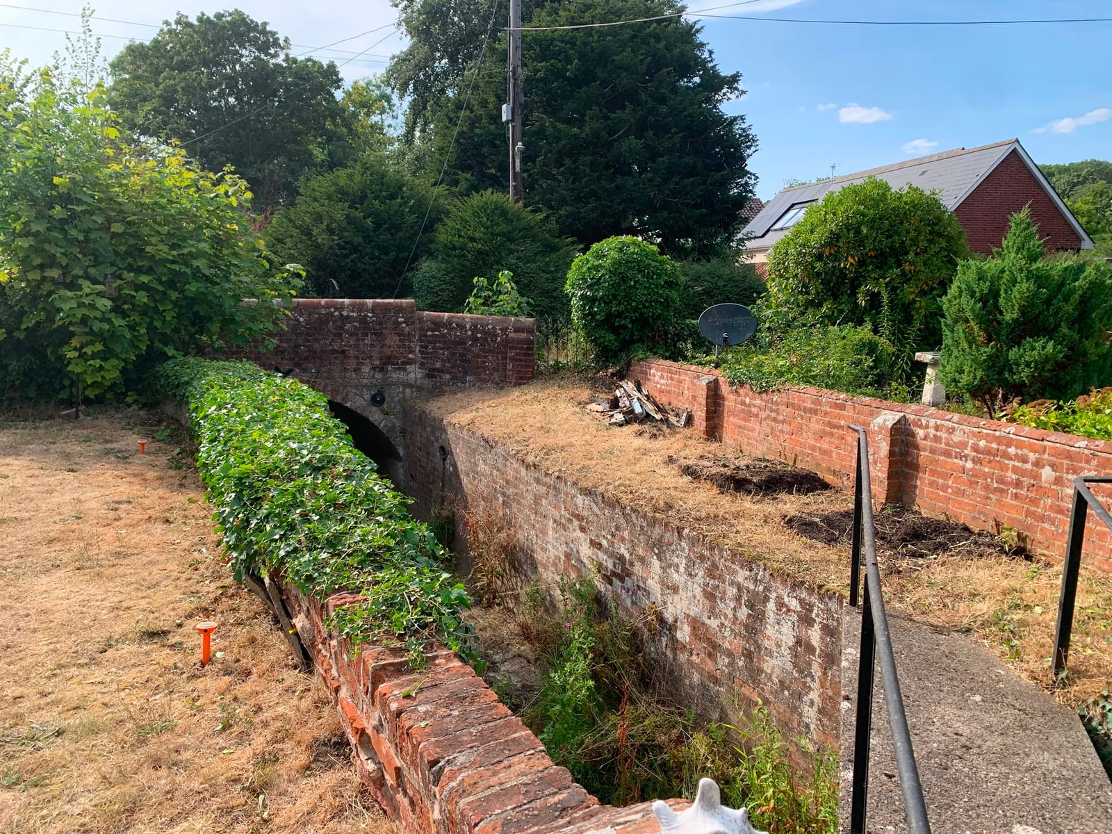 Overgrown brick-walled garden bed in Kelsale, before and after clearing the ivy and weeds (after)